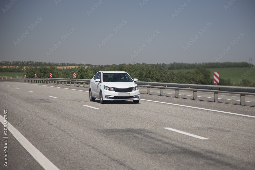 White hatchback rides on the highway