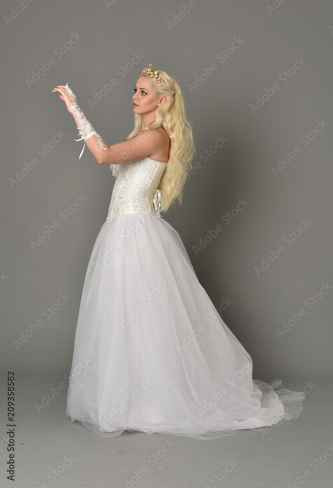 full length portrait of blonde girl wearing white corset gown. standing pose on grey studio background. full length portrait of blonde girl wearing white corset gown. standing pose on grey studio background.