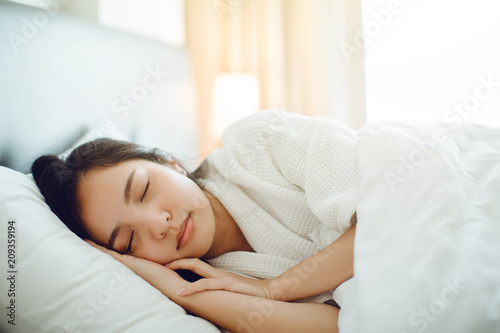 Young beautiful woman sleeping in her bed and relaxing in the morning