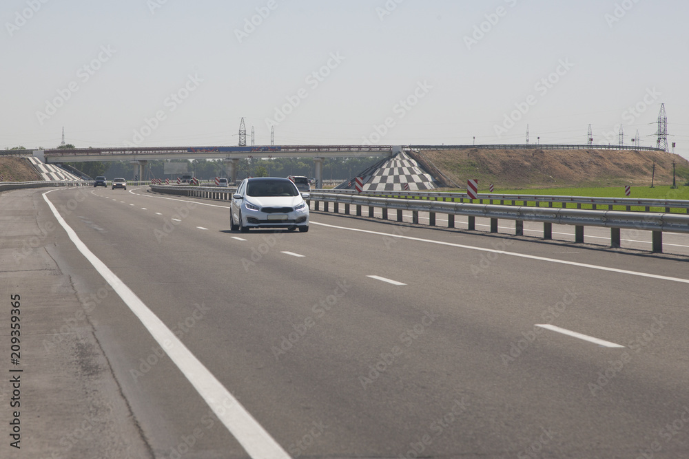 Several cars are driving along the highway. In the background, the bridge