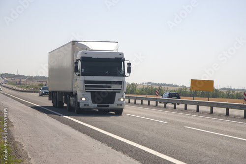 A truck with a trailer is driving along the highway