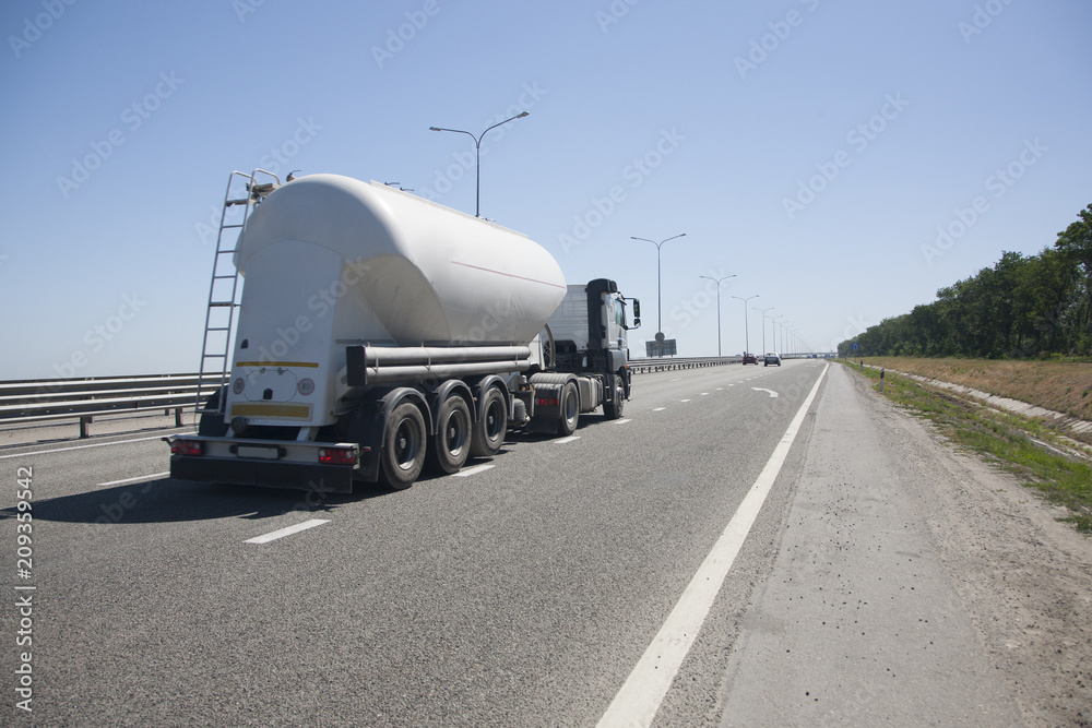 A truck with a trailer is driving along the highway