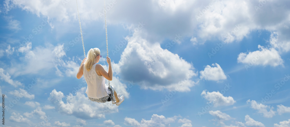 Blonde girl with ponytail flying high among the white clouds on a swing - obrazy, fototapety, plakaty 