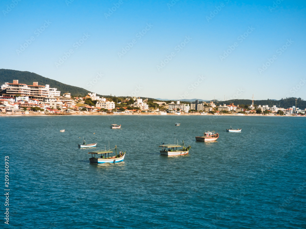 Fishermen's boats in the ocean at Ingleses beach in the mullet season, city in the background (Florianopolis, Brazil)