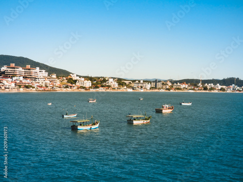 Fishermen's boats in the ocean at Ingleses beach in the mullet season, city in the background (Florianopolis, Brazil)