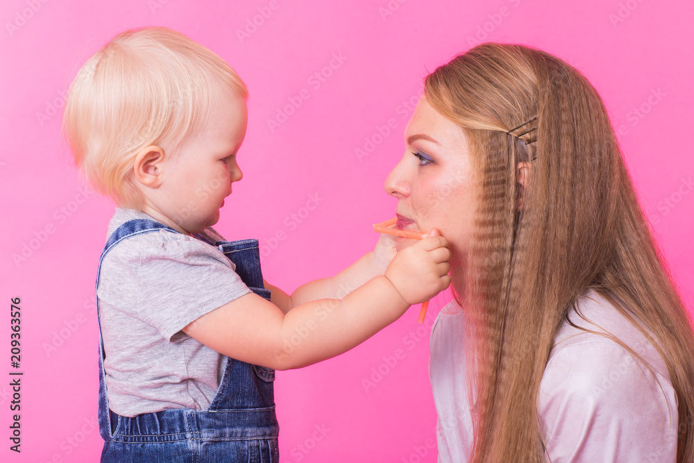 happy little girl and her mother having fun over pink background happy little girl and her mother having fun over pink background