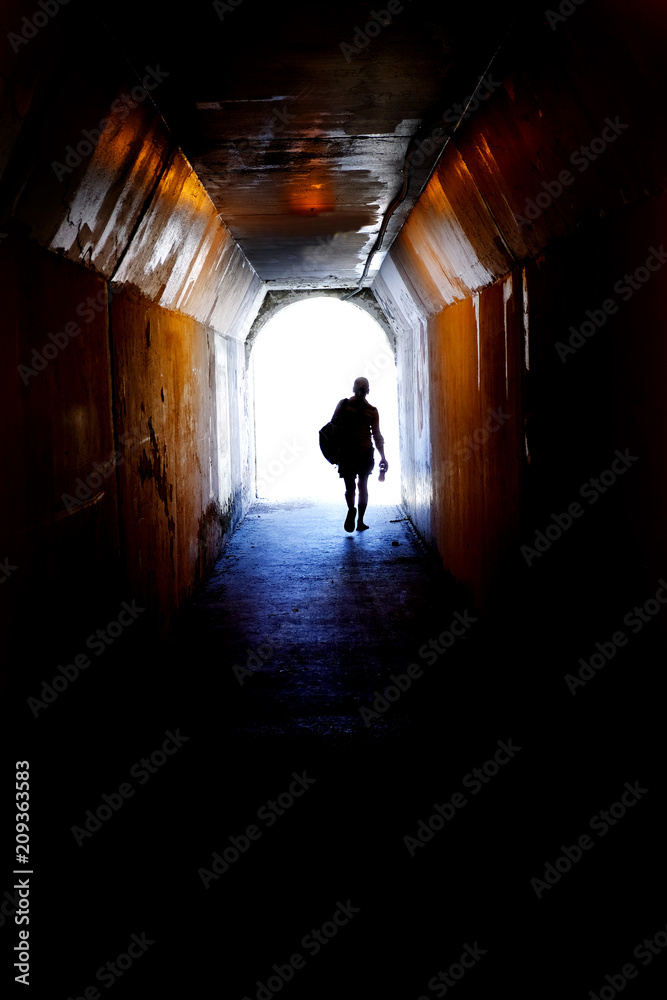Person Walking to End of Tunnel Towards the Light Symbolic