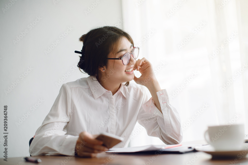 woman using smart phone and laptop in office