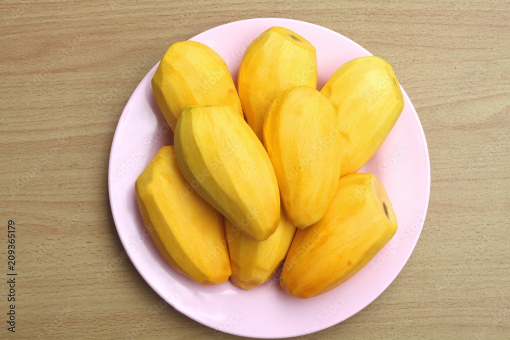 Ripe mango in a pink plate on a wooden background. Ripe mango in a pink plate on a wooden background.