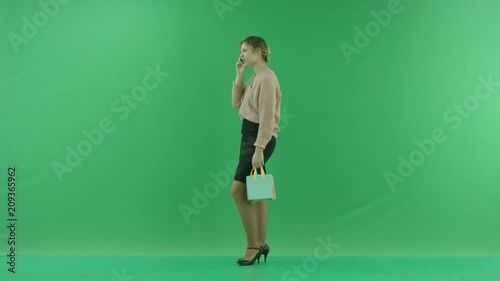 Pretty shopping woman with shopping bags. Female shopper holding shopping bags sideways on green background in studio. photo