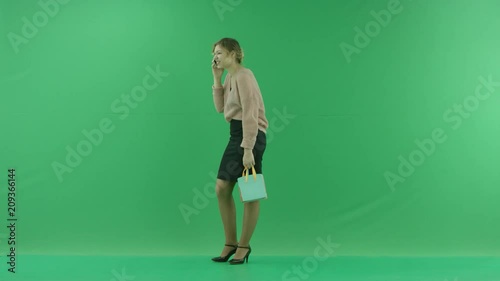 Pretty shopping woman with shopping bags. Female shopper holding shopping bags sideways on green background in studio. photo