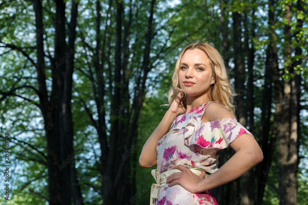 Girl with light wavy hair against the background of trees in the park Girl with light wavy hair against the background of trees in the park