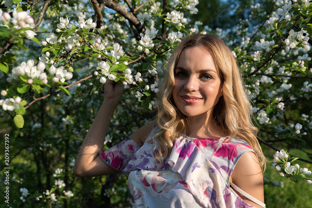 A girl with light wavy hair near blossoming trees in the park A girl with light wavy hair near blossoming trees in the park