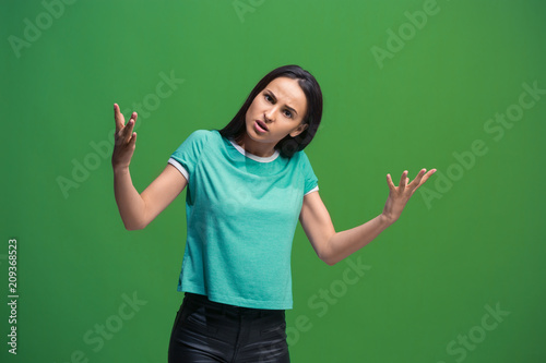 Beautiful female half-length portrait isolated on green studio backgroud. The young emotional surprised woman