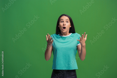 Beautiful woman looking suprised isolated on green