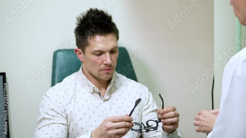 young man at a reception with an ophthalmologist, checks vision, having eye examination with phoropter, optometrist trial frame, visual inspection device. in doctor's office photo