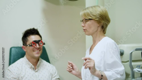 female doctor ophthalmologist is checking the eye vision of handsome young man in modern clinic. Doctor and patient in ophthalmology clinic. Doctor is giving advices. photo