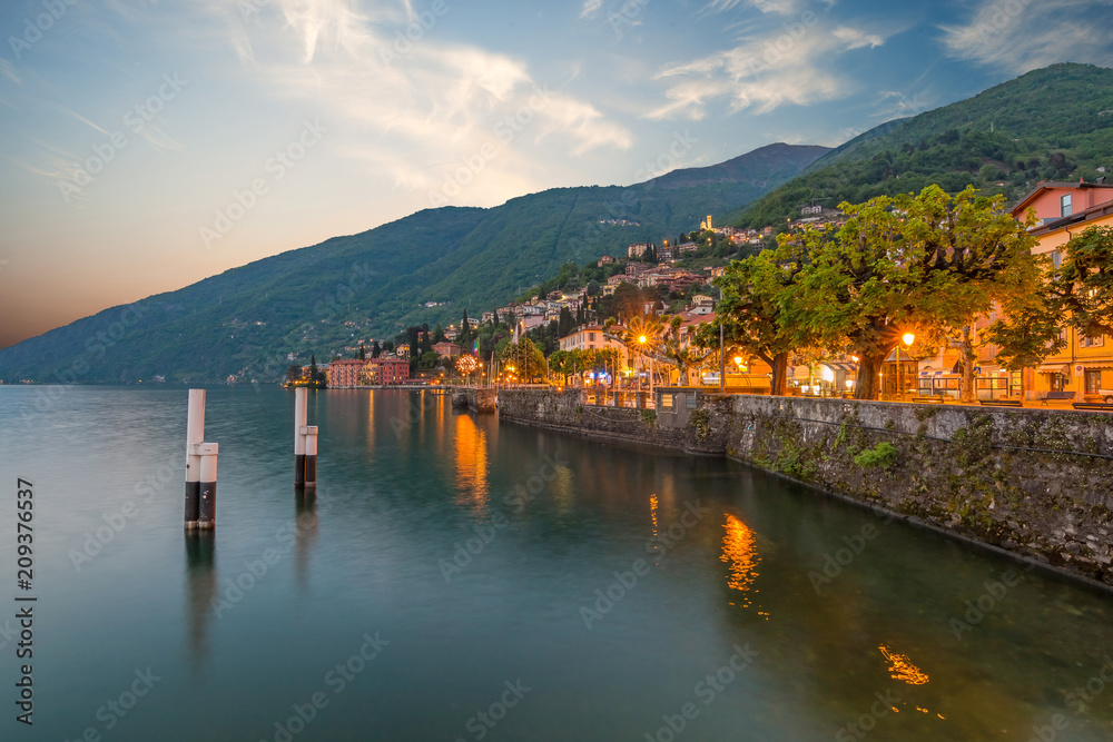 holidays in Italy - a view of a city Bellano, with the most  beautiful lake in Italy - Lago di Como in background. Area of famous Belano City at sunset. Harbor with boats and yachts