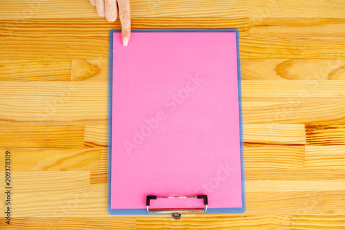 Office Hand Holding a Folder with a Pink Color Paper on the Background of the Wooden Table. Copyspace. Place for Text.