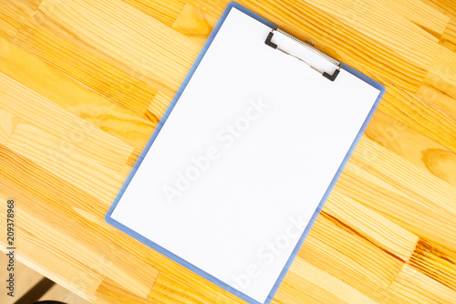 Office Hand Holding a Folder with a White Color Paper on the Background of the Wooden Table. Copyspace. Place for Text. photo