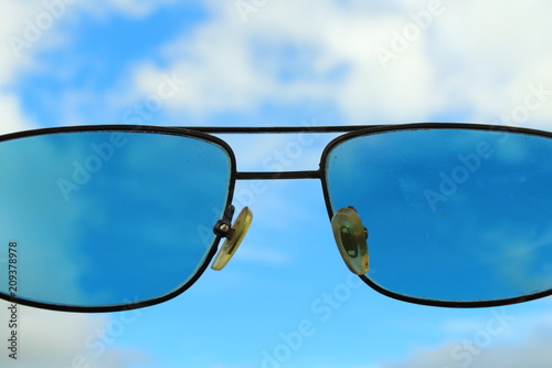 A look at the sky through sunglasses. Beautiful blue sky and white clouds. Close-up. Background.