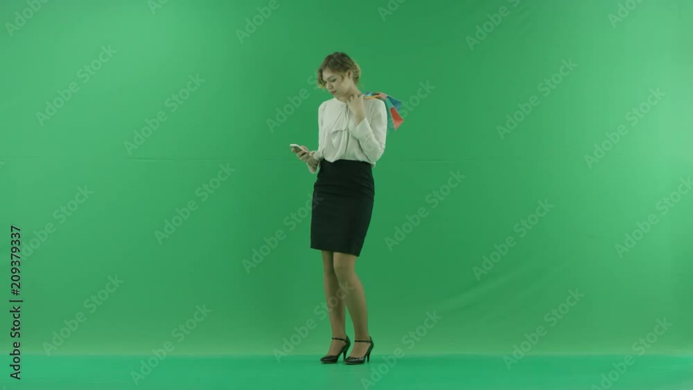 Pretty shopping woman with shopping bags. Female shopper holding shopping bags sideways on green background in studio. Pretty shopping woman with shopping bags. Female shopper holding shopping bags sideways on green background in studio.