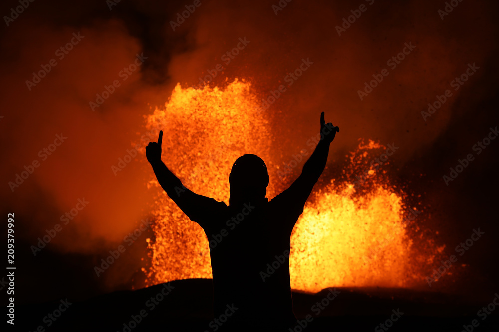 Victory pose in front of a lava fountain of the volcanic eruption of Kilauea in Hawaii