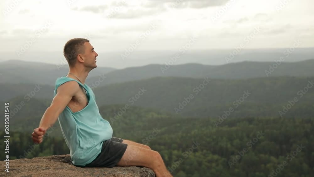 A man sits on the edge of a cliff and shouts. A man sits on the edge of a cliff and shouts.