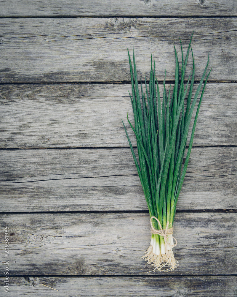 Fresh green onion on a wooden background. Top view. Free space for your text. Fresh green onion on a wooden background. Top view. Free space for your text.