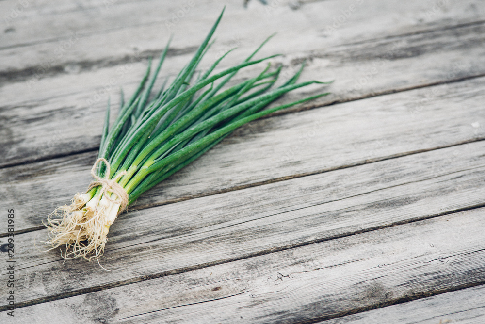 Fresh green onion on a wooden background. Top view. Free space for your text. Fresh green onion on a wooden background. Top view. Free space for your text.