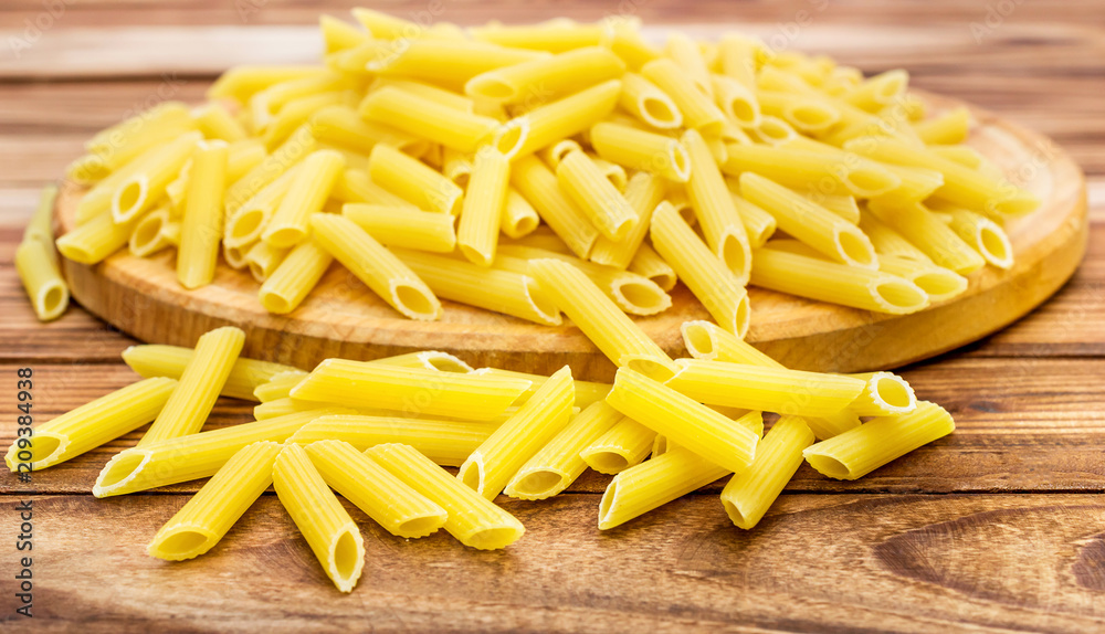 Cutting board with raw pasta on wooden table. Close up. Cutting board with raw pasta on wooden table. Close up.