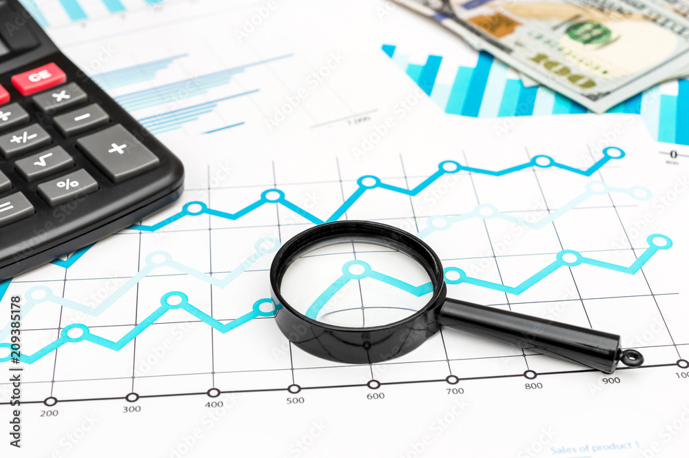 Magnifying glass with money and calculator on financial documents. Top view. Magnifying glass with money and calculator on financial documents. Top view.