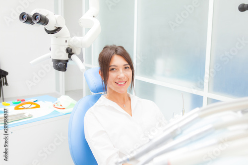 young beautiful girl in a dental chair smiling, looking at the camera