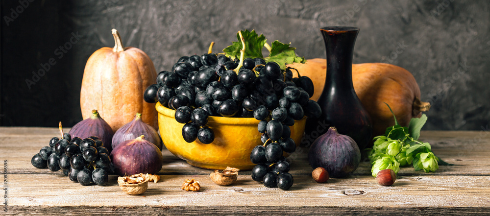Fototapeta jesień martwa natura, dynia, winogrona, figi i orzechy na drewnianym stole, ciemne tło