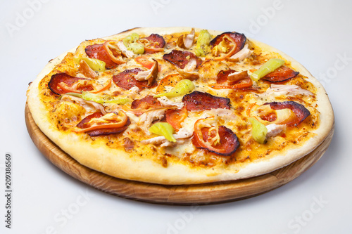 juicy cheese pizza with bits of bacon, with meat of chicken and with pepper is on a round board on a white background