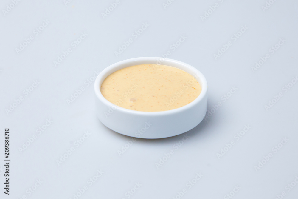 a plate of sauce with sour cream stands on a table on a white background a plate of sauce with sour cream stands on a table on a white background