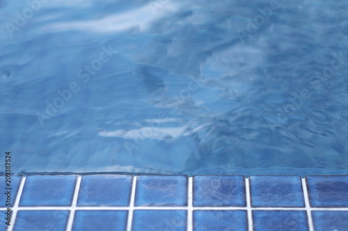 Stone side and surface of clear blue water in the pool