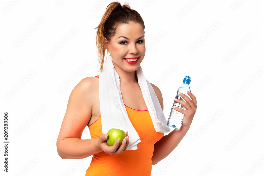 Healthy and Fitness lifestyle concept - beautiful young woman in sportswear with towel, water and green apple on a white background. Healthy and Fitness lifestyle concept - beautiful young woman in sportswear with towel, water and green apple on a white background.