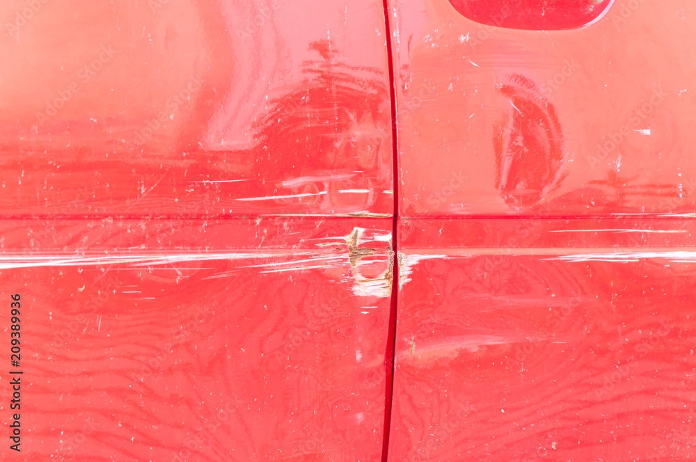 Red scratched car with damaged paint in crash accident or parking lot