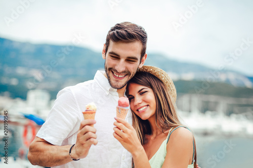 Happy couple having date and eating ice cream on vacation. Sea background.
