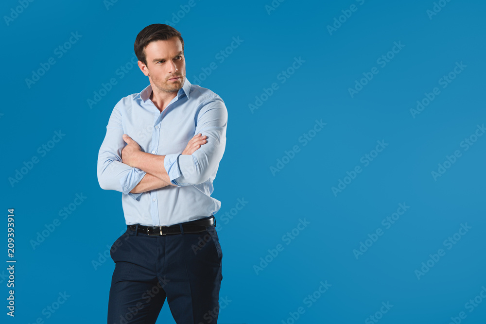 serious man standing with crossed arms and looking away isolated on blue serious man standing with crossed arms and looking away isolated on blue