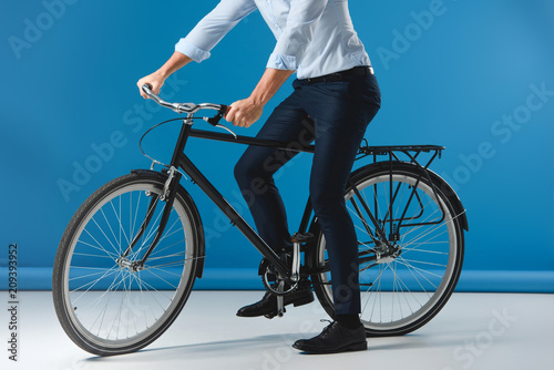 cropped shot of stylish man sitting on bicycle on blue