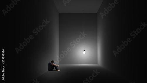 A man is sitting depressively in a room with a lightbulb