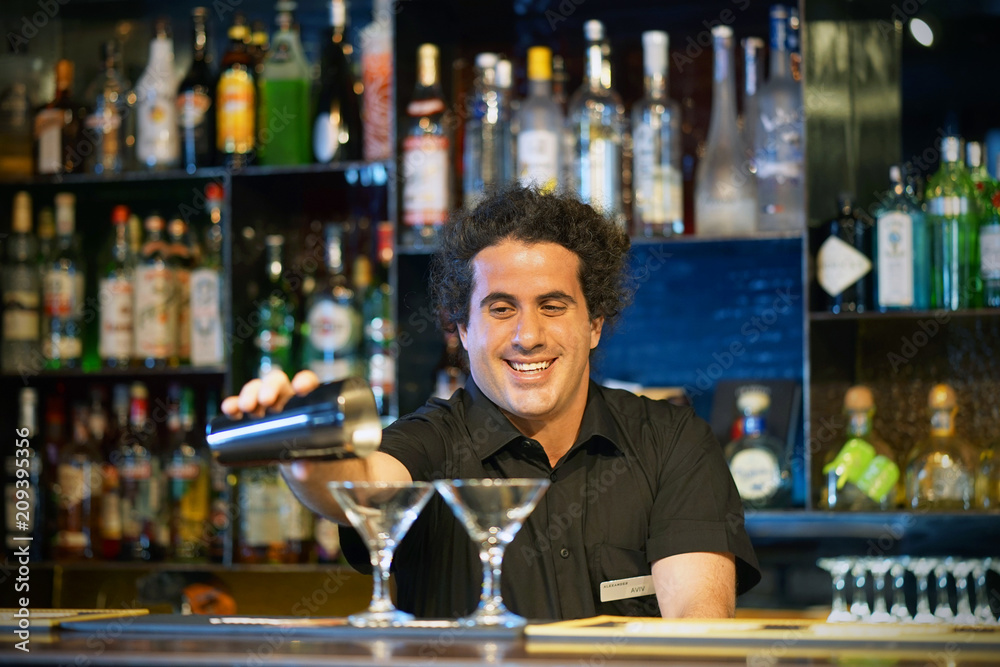 Professional barman man pours a fresh cocktail to the customers of the hotel bar. The concept of service. Focus on the bartender.