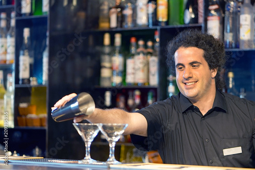 Professional barman man pours a fresh cocktail to the customers of the hotel bar. Focus on the bartender. The concept of service. Focus on the bartender. photo