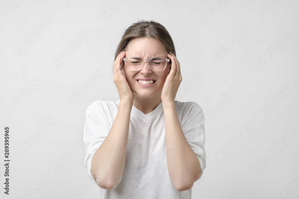 European girl in white t-shirt suffers from terrible headaches and compresses the head with fingers. European girl in white t-shirt suffers from terrible headaches and compresses the head with fingers.