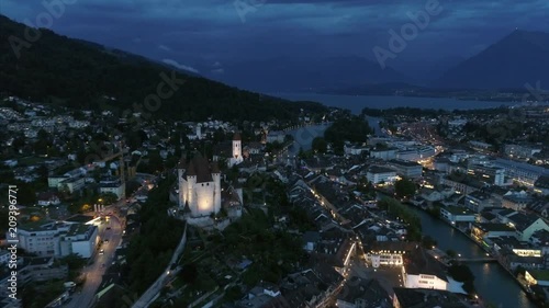 Drone shot of Thun, Bern, Switzerland. Backwardsaerial of Thun City and Aare river at dusk. Drone is flying backwards. Footage captures the Thun Church. photo