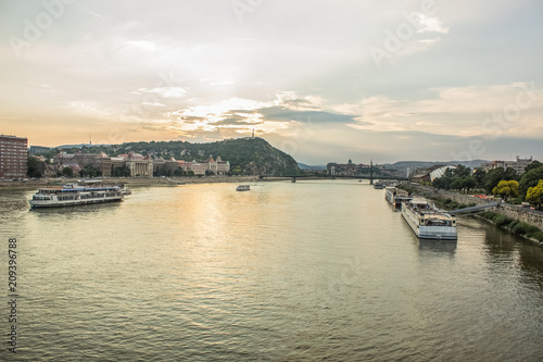 evening urban city scape of waterfront with river and ships in sunset time with sun rays and soft colors