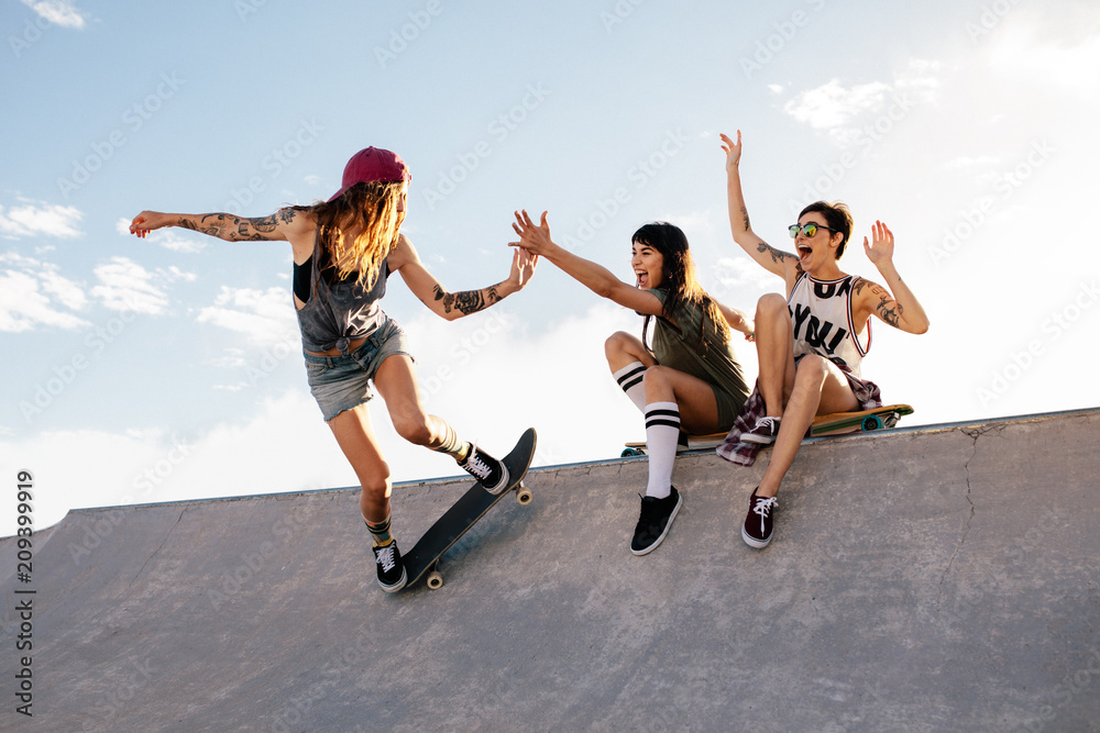 Foto Stock Skater girl riding skateboard at skate park with friends | Adobe  Stock