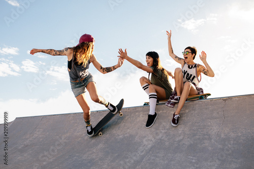 Skater girl riding skateboard at skate park with friends photo